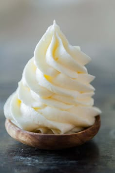 a wooden bowl filled with whipped cream on top of a table