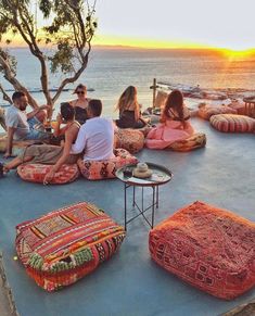 group of people sitting on the ground with colorful cushions and pillows in front of them