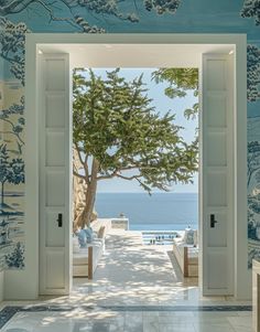 an open door leading to the ocean with trees on both sides and blue wallpaper