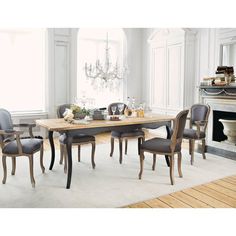 a dining room table with chairs and a chandelier hanging from the ceiling in front of a fireplace