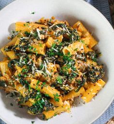 pasta with spinach and parmesan cheese in a white bowl on a blue tablecloth