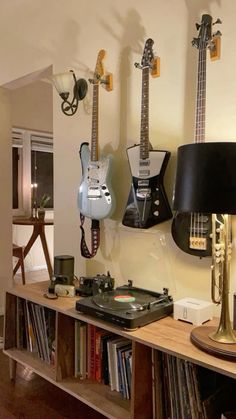 guitars are hanging on the wall above a record player's turntable and lamp