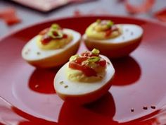 deviled eggs with toppings on a red plate