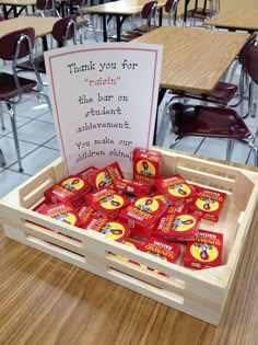 a wooden crate filled with candy sitting on top of a table next to a sign