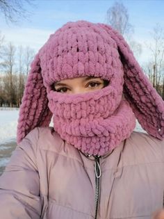 a woman wearing a pink knitted hat and scarf over her face in the snow