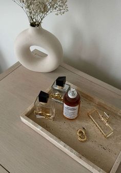 a vase with flowers and other items on a wooden table next to a bottle of perfume