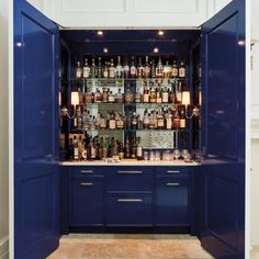 a blue cabinet filled with lots of bottles next to a wall mounted shelf full of liquor