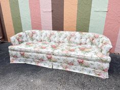 a floral couch sitting in front of a colorful wall with vertical striped walls behind it