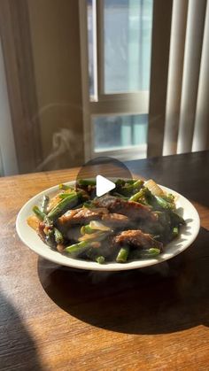 a white plate topped with meat and asparagus on top of a wooden table