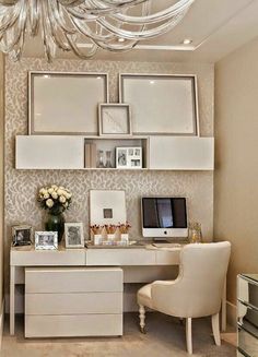 a white desk with a computer on top of it and some pictures hanging above the desk