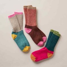 three pairs of colorful socks sitting on top of a white table next to each other