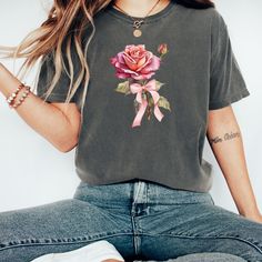 Everyone's favorite Comfort Colors relaxed fit tee! Enjoy as styled or size up for that comfy, oversized 90's fit. Embrace your inner trendsetter with this playful coquette addition to your wardrobe. 🎀 Feminine Flair: The Rose and bow add a touch of coquette charm to this adorable tee. 🌹 High-Quality Craftsmanship of Comfort Colors: Made with ethically grown and harvested, 100% ring-spun,  US cotton for long-lasting comfort. Our pre-shrunk tee shirt is designed to stand the test of time, keepi Cheap Pink T-shirt With Rose Print, Affordable Pink Rose Print T-shirt, Coquette Clothing, Die Rose, 90s Fits, Bow Shirt, Rose T Shirt, Cute Rose, Bow Shirts