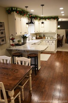 the kitchen is decorated for christmas with garland on the ceiling and lights over the island