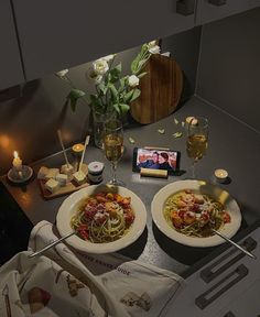 two plates of spaghetti and wine on a table