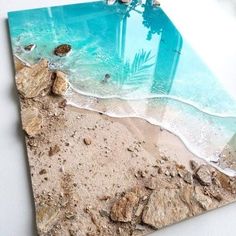 a beach scene with rocks and water in the sand, on top of a white surface