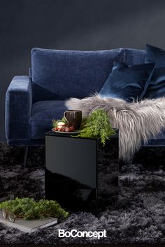 a blue couch sitting on top of a rug next to a table with a coffee cup