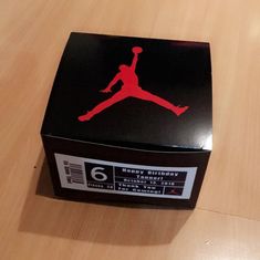 the box is black with red air jordan logo on it, and sits on top of a wooden table