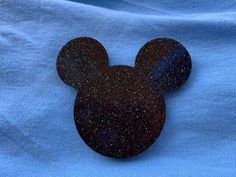 a close up of a mickey mouse head on a blue shirt with black speckles