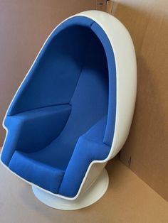 a blue and white chair sitting on top of a cardboard box next to a wall