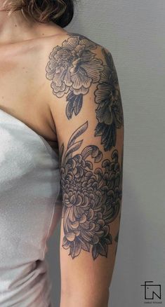 a woman with a tattoo on her arm is wearing a white dress and has flowers on it