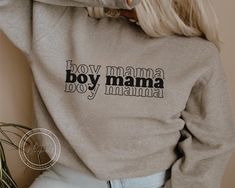 a woman with blonde hair wearing a grey sweatshirt that says boy mama, boy mama