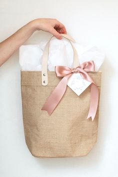 a hand holding a brown bag with pink ribbon