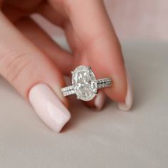 a woman's hand with a ring on her finger and an oval shaped diamond in the middle