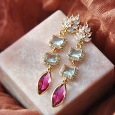 Make a statement with these vibrant wedding earrings which are created with colorful faceted glass in aqua blue and magenta pink. The ornate leaf earring posts are accented with cubic zirconia for added sparkle and secured to geometric shapes framed with tiny cz for a unique look. Whether searching for statement earrings for your wedding day, or something for your next special occasion, all of my jewelry arrives gift wrapped ready for gift giving.        Measurements: The length of the colorful Bridal Earrings Statement, Boho Bridal Earrings, Earrings Summer, Summer Earrings, Wedding Boho, Colorful Wedding, Earrings Bohemian, Summer Earring, Boho Bridal