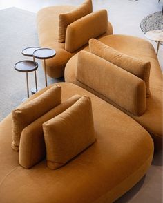 an orange couch and two side tables in a room with concrete flooring on the ground