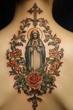 A religious-themed tattoo on a person's back featuring a figure in prayer, surrounded by floral designs and topped with a cross. Holy Mary Tattoo, Tattoos Latin, Catholic Tattoo Ideas, Catholic Tattoos For Women, Virgin Mary Tattoos, Mary Tattoos, Rosary Bead Tattoo, Saint Tattoo