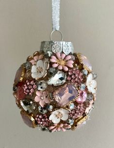 a christmas ornament hanging on a wall with flowers and jewels in the center