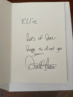 an open book with writing on it and a handwritten note attached to the cover