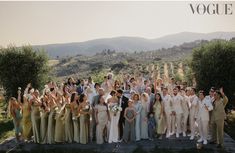 a large group of people posing for a photo in front of some hills and trees