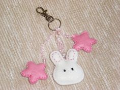 a keychain with two pink stars and a white bunny face on it's side