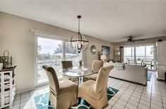 a dining room table with four chairs next to a living room and kitchen area in front of a sliding glass door