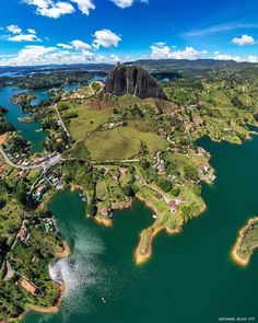 an aerial view of a lake surrounded by lush green trees and mountains in the distance