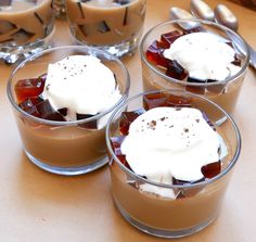 four desserts in small glass dishes with whipped cream on top and chocolate pudding below