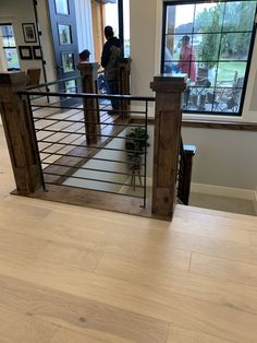 the inside of a house with people standing in the living room and looking out the window