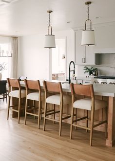 a kitchen with an island and chairs in the center, along with a dining room table