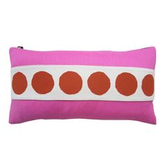 a pink and white pillow with orange polka dots on the front, sitting against a white background