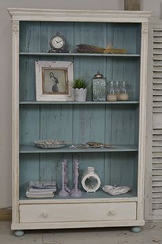 an old white bookcase with pictures and other items on it