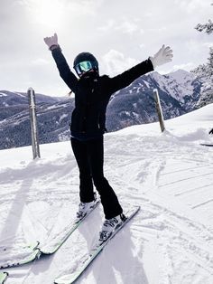 a person standing on skis in the snow with their arms up and hands raised