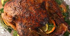 a roasted turkey on a platter with lemons and herbs