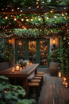 an outdoor dining area is lit up with candles and greenery on the outside wall