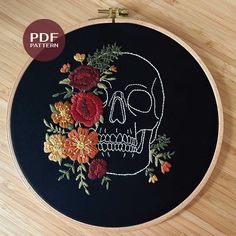 a skull with flowers in it on a wooden table next to a black wall hanging