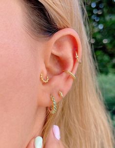 a close up of a person wearing gold ear cuffs and an ear cuff with small beads