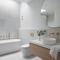 a white bathroom with a tub, sink and mirror in the corner next to it