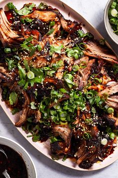 a platter filled with meat and veggies next to bowls of dipping sauce