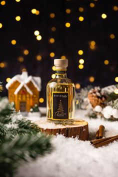 a bottle of liquor sitting on top of a wooden stump in the snow next to christmas decorations