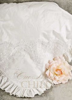 a white pillow with a flower on it and a lace border around the edges that has been ruffled